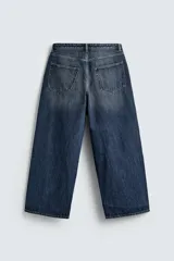 Pantalón de jeans de algodón, corte baggy fit, tiro medio, con efecto lavado en tonos grises y verdes. Presenta cinco bolsillos y cierre frontal con cremallera y botón.