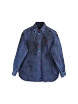 Camisa de jean azul oscuro con lavado gastado, corte oversized, cuello clásico, cierre frontal con botones metálicos, mangas largas con puños abotonados y bordado "PASTICHE" en el pecho.