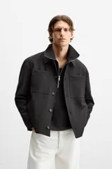 Sobrecamisa negra de corte cuadrado con cuello solapa, manga larga con puños abotonados, bolsillos de parche en el pecho, bolsillos laterales y cierre frontal con botones.