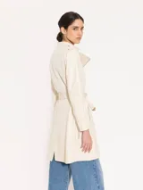 Tapado color crema confeccionado en cuero ovino, con largo hasta arriba de la rodilla. Presenta costadillos, espalda y bajo mangas en complemento al tono que aportan textura. Incluye cinturón en cuero base, bolsillos ojal verticales en el frente y canesú matelaseado. El acceso es mediante cierre metálico al frente.