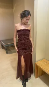 Vestido strapless color borgoña con frunces y falda transparente con tajo lateral.