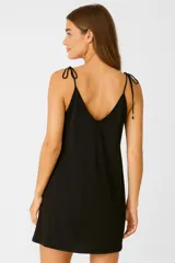 Vestido corto color crema, de viscosa, corte evasé, escote en V y tirantes finos con detalle de nudo. Incluye bolsillos laterales.