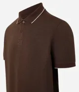 Chomba de piqué color marrón con cuello polo, tapeta de tres botones y mangas cortas.