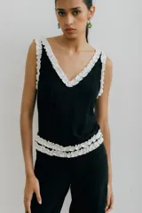 Musculosa negra con escote en V y volados blancos en el escote y las sisas.