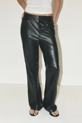 Pantalón negro de tiro medio, con trabillas en la cintura, cinco bolsillos y pernera ancha. Cierre frontal con cremallera, botón oculto y gancho metálico.