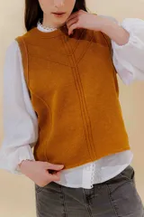 Chaleco tejido color mostaza con bordado artesanal en forma de V.