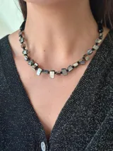 Collar corto con cuentas de nácar con subtono negro, mostacillas y cristales checos. Se cierra con cadena de acero quirúrgico y ganchito para regular el largo.