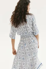Vestido midi con estampado floral en tonos celeste y azul, cuello camisero, botonadura frontal, mangas cortas raglán, elástico en la cintura y cinturón extraíble para atar.