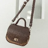 Cartera bandolera de cuero color marrón con asa corta superior y correa larga ajustable.