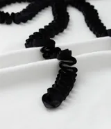 Remera blanca de algodón con cuello redondo, mangas cortas y aplicación de cinta contrastante formando un lazo negro en el frente.