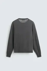 Jersey negro de lana con acabado mercerizado, corte relaxed fit, cuello redondo y mangas largas con terminaciones en rib.