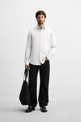 Camisa celeste de corte slim fit, confeccionada en tejido de algodón. Tiene cuello italiano, mangas largas con puños abotonados y cierre frontal con botones.