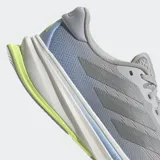 Championes de running Adidas Supernova Rise 2, color gris con detalles en azul claro y suela blanca con inserción de espuma verde lima en el talón. Presentan un exterior de malla técnica y mediasuela con tecnología Dreamstrike+.