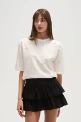 Remera blanca de algodón con tachas plateadas y cuello redondo.