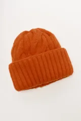 Gorro de punto color naranja quemado, con diseño trenzado en la corona y borde doblado de punto acanalado.