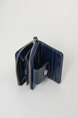 Billetera color champagne con acabado brillante, cierre zip y compartimientos internos.