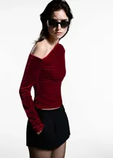 Top de terciopelo rojo con un solo hombro, manga larga y frunces laterales.