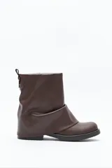 Bota de caña baja confeccionada en poliuretano de acabado liso con diseño minimalista. Presenta una estructura flexible con efecto fruncido, puntera redondeada, suela plana y cierre de cremallera posterior con detalle metálico.