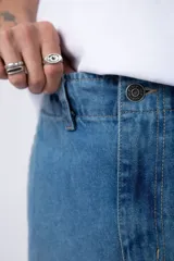 Pantalón jean azul de corte ancho, estilo cargo, con bolsillos laterales y detalles metálicos.