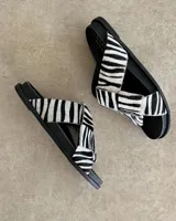 Sandalias bajas de cuero negro con tiras anchas cruzadas y plantilla anatómica color camel.