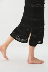 Vestido negro de tejido de punto calado, largo midi, con escote en V y tirantes anchos.