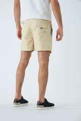 Short de baño color arena con estampado geométrico en tonos celeste y blanco. Cuenta con cintura elástica ajustable con cordón, dos bolsillos laterales, un bolsillo trasero, suspensor interno y logo bordado.