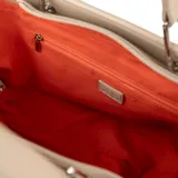 Cartera tipo shopper color taupe, confeccionada en símil cuero texturizado. Tiene doble asa de mano, correa bandolera regulable y herrajes plateados. El acceso es con cierre y cuenta con un compartimento principal con bolsillos internos, uno con cierre y dos abiertos.