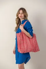Bolso tipo tote con estampado a cuadros rojos y blancos, con doble asa de tela.