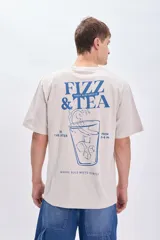 Camiseta manga corta oversize color gris claro con estampa azul en la espalda que incluye texto "Fizz & Tea" y el dibujo de un vaso con hielo.