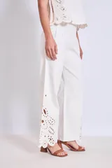 Pantalón blanco de corte ancho con bordados calados en forma de hojas en el ruedo.