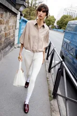 Chaqueta bomber color beige con cuello solapa y manga larga. Tiene bolsillos delanteros y bajo ajustable con cordones. Cierre frontal con botones ocultos.