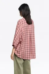 Camisa blanca de corte ancho y silueta relajada, con cuello camisero, botones frontales, manga 3/4 ancha con puño y bolsillo de plastrón en el pecho.