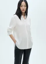 Camisa blanca de tejido fluido con cuello redondo y escote de pico.