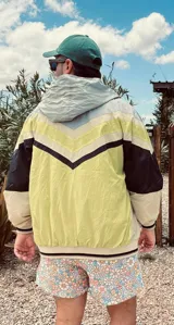 Campera deportiva con capucha, color gris, beige, negro y amarillo.