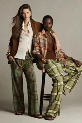 Pantalón de tiro medio con estampado de cuadros color verde y marrón, confeccionado en hilatura de viscosa. Tiene bolsillos delanteros, corte crop y bajo acampanado. Cierre frontal con cremallera y botón.