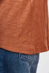 Remera de algodón peruano color terracota, con textura jaspeada, corte holgado y ruedo redondeado e irregular.