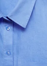 Camisa blanca de lino con cierre de botones, bolsillo de parche en el pecho, manga larga con puños abotonados, diseño recto y cuello camisero.