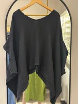 Blusa negra de manga corta, con escote en V y corte amplio con terminaciones asimétricas en forma de picos.