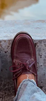 Mocasines náuticos color borgoña de cuero con cordones y suela marrón.