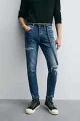 Pantalón de jean azul oscuro con efecto lavado y roturas en las rodillas, de corte ajustado al cuerpo desde la cintura hasta el tobillo.