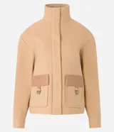 Saco color beige en polyvelour, con cuello alto, mangas largas, sisas desplazadas, cierre delantero y bolsillos con detalle en PU.