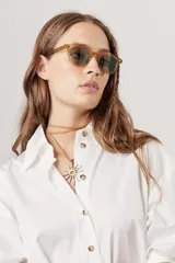 Collar con diseño en forma de sol, fabricado con un cordón de cuero y un colgante metálico.