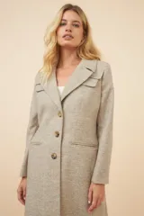 Tapado largo color beige con cuello solapa y corte recto. Cierre frontal con botones, detalles aplicados en la parte delantera, tajo en la espalda y bolsillos ojal con tapa. Con forro. Hecho en Uruguay con tela 100% lana fina sin teñir.