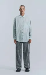 Camisa manga larga verde agua con bolsillo en el pecho, de calce oversize confeccionada en textil plano fresco y liviano.