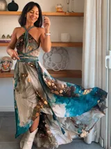 Vestido largo de tela fluida, color verde esmeralda con estampado abstracto en tonos turquesa y detalles dorados. Diseño asimétrico con un solo tirante tejido en el hombro.