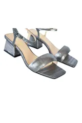 Sandalias plateadas con textura, tira ancha sobre los dedos, pulsera ajustable al tobillo y tacón geométrico.