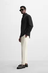 Pantalón negro de corte cropped, con cintura elástica ajustable con cordón, bolsillos laterales y traseros de vivo. El bajo tiene terminación con vuelta.
