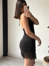 Vestido corto color marrón, con escote halter, espalda descubierta, corte ajustado y falda con volados.
