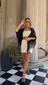 Vestido largo sin mangas, color blanco roto, confeccionado en tejido de red con trama abierta. Se lleva sobre una prenda interior blanca ajustada.