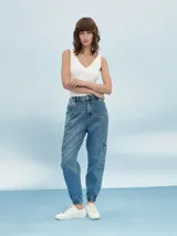 Pantalón de jean gris claro con efecto lavado, corte recto, tiro alto, bolsillos laterales y tobillos ajustados con elástico.